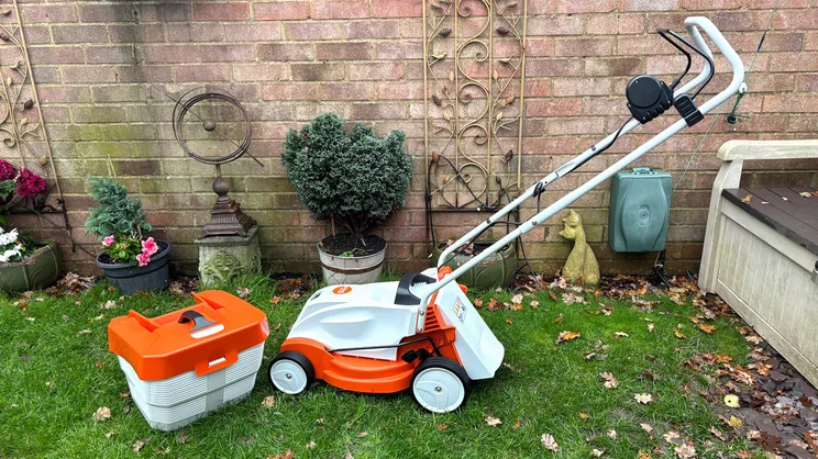 The Stihl RMA 235 lawn mower with grass collector removed and placed in front of it