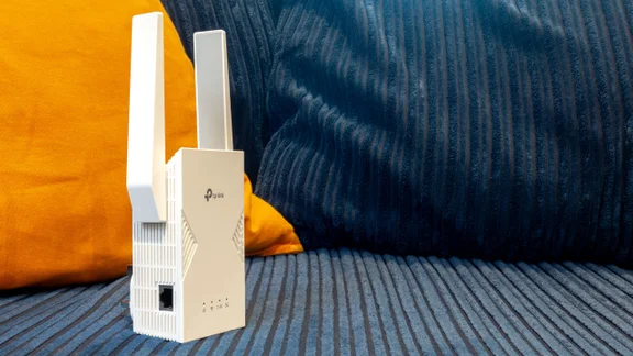The TP-Link-RE235BE pictured from in front on a blue and orange corduroy sofa
