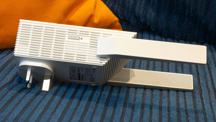 The TP-Link-RE235BE pictured from the right side on a blue and orange corduroy sofa