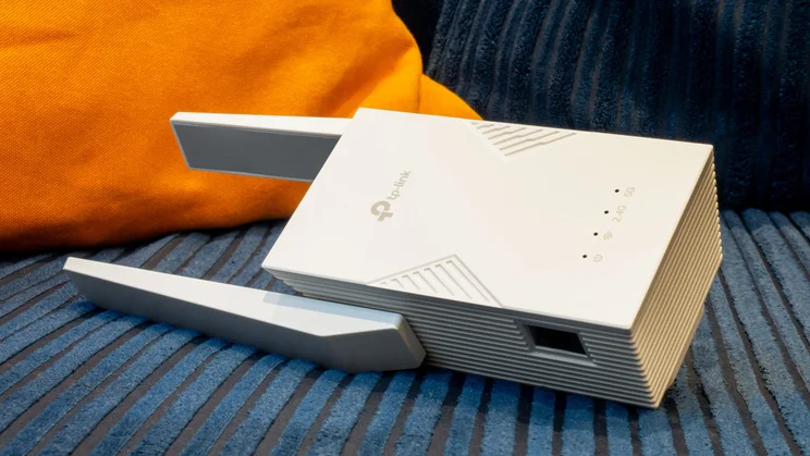 The TP-Link-RE235BE pictured from the left side on a blue and orange corduroy sofa