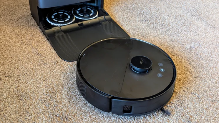 The Tapo RV50 Pro robot vacuum, pictured exiting its docking station on brown carpet