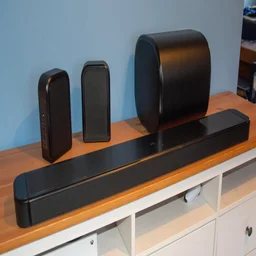 Left view of the JBL Bar 1300 MkII soundbar, subwoofer and detachable rear speakers on a wooden TV stand