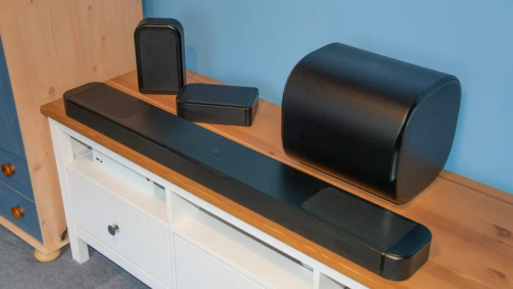 Right view of the JBL Bar 1300 MkII soundbar, subwoofer and detachable rear speakers on a wooden TV stand
