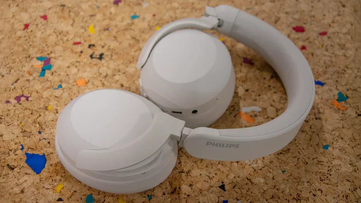 The Philips H8000E over-ear headphones folded inwards slightly on a cork table