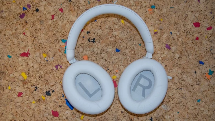 The Philips H8000E over-ear headphones on a cork table with the inside of their earcups facing upwards