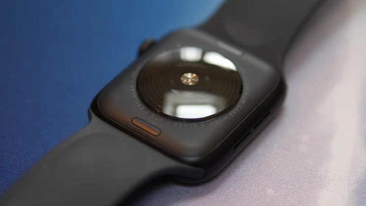 A close up of the Apple Watch SE 3's rear, with the watch lying flat on a blue and white mat