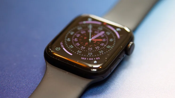 Apple Watch SE 3 lying flat on a blue and white mat, at an angle, showing the Exactograph watch face