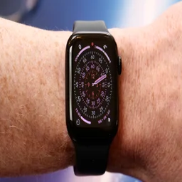 Apple Watch SE 3 on a wrist showing the Exactograph watch face with a blue background