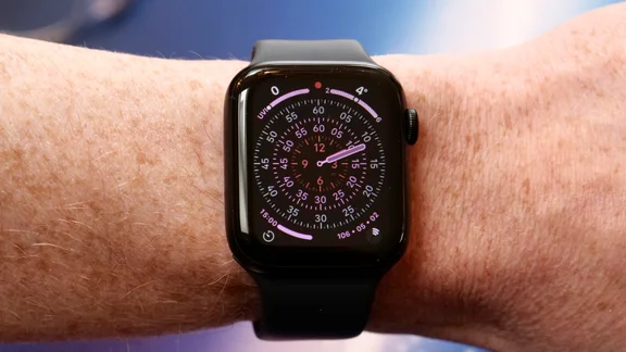 Apple Watch SE 3 on a wrist showing the Exactograph watch face with a blue background