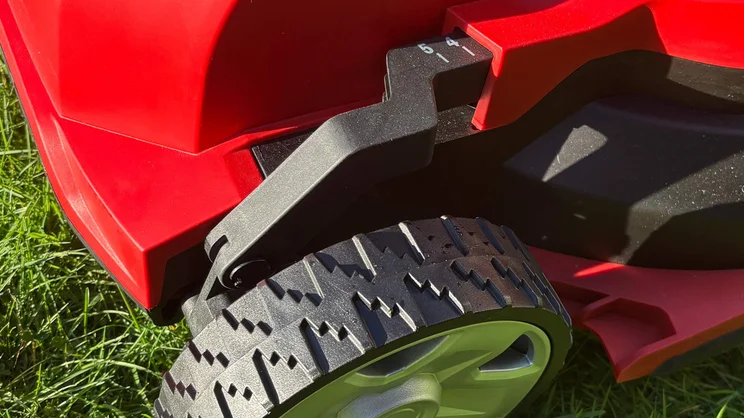 A closeup of the Cobra MX4340VX lawn mower's height indicator, next to its front left wheel