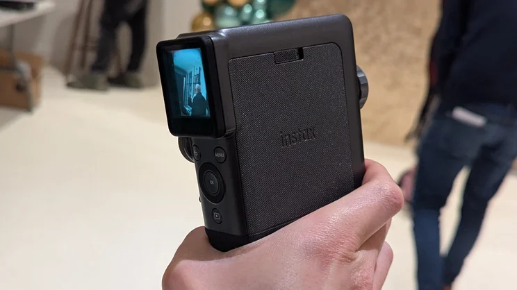 A POV the Instax Mini Evo Cinema, showing the side of the camera with logo