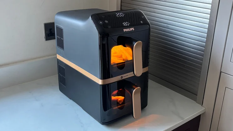 A chicken and chips cooking in the Philips 4000 Series Stacked Dual Basket Air Fryer, on a kitchen worktop