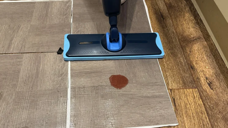 The Philips OneUp mop being used to clean a blackcurrant squash stain from a sample of vinyl flooring