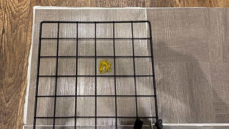 A mustard stain on a sample of vinyl flooring, with a squared grid placed on top