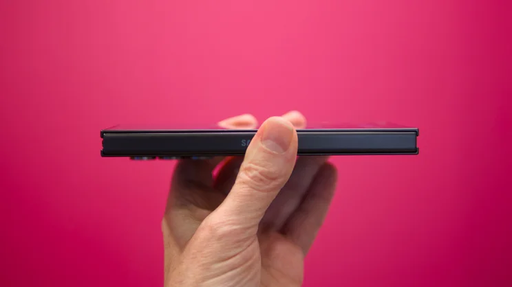 The Samsung Galaxy Z TriFold, folded, pictured from the left edge against a pink background