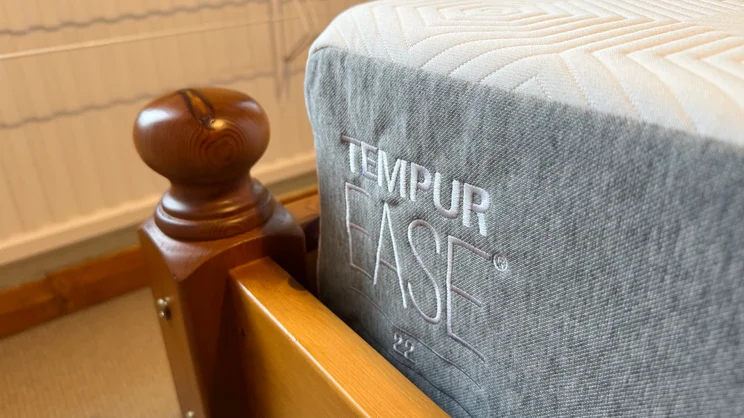 The corner of the TEMPUR EASE mattress, on a wooden bed frame