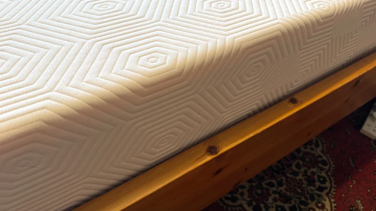 A side of the TEMPUR EASE mattress, on a wooden bed frame
