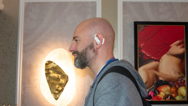 The Anker Soundcore AeroFit 2 Pro being worn by a journalist in a hotel suite in Las Vegas