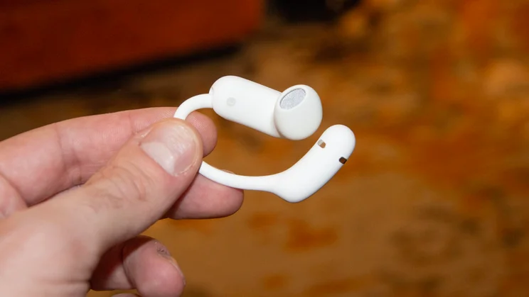 One of the Anker Soundcore AeroFit 2 Pro earbuds being held between a thumb and forefinger