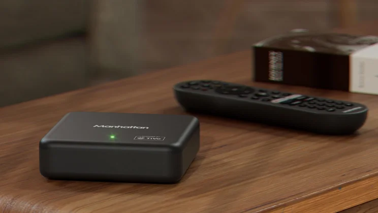 The Manhattan Aero 4K TV Streamer box and its remote control on a wooden table
