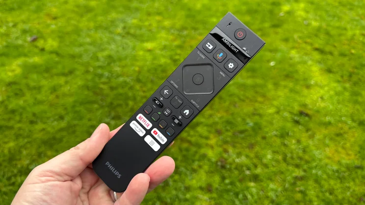 The remote control included with the Philips OLED810 TV being held in a hand