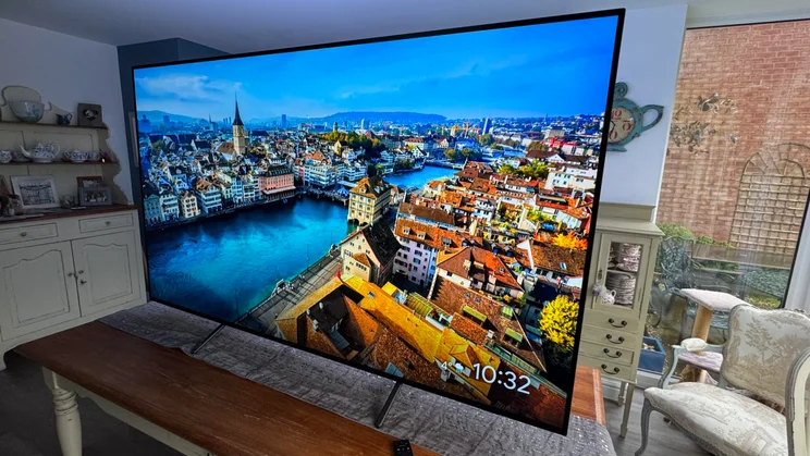 Right view of the Philips OLED810 TV displaying a riverside city space while on a table in an open-plan kitchen