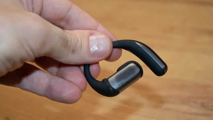 One of the Shokz OpenFit Pro earpieces being held in a hand