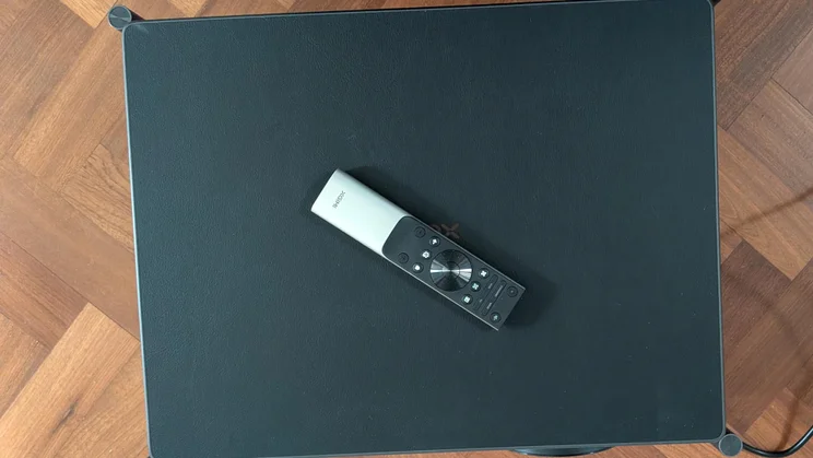 Top-down view of the XGIMI Titan projector with the included remote control lying on it