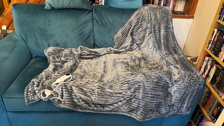 The Bedsure Heated Blanket Electric Throw draped over a blue sofa