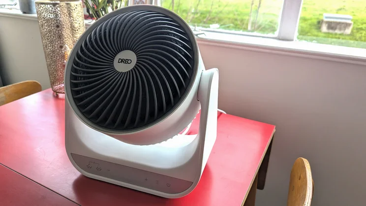 The Dreo Smart Whole Room Heater 714s on a red table, in front of a window