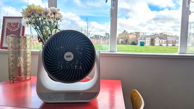 The Dreo Smart Whole Room Heater 714s on a red table, in front of a window
