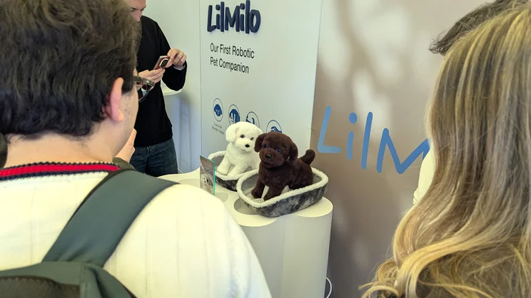 Journalists crowding round two of Ecovacs' LilMilo robot dogs