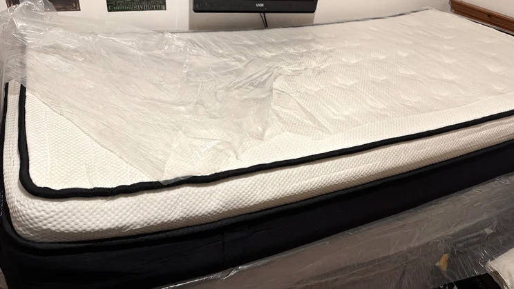 The Origin LumbarCloud mattress unpackaged and deflating on a bed