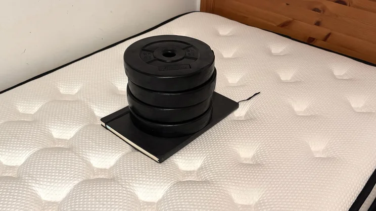 Testing the sinkage of the Origin LumbarCloud mattress's surface, using a notebook and series of weights