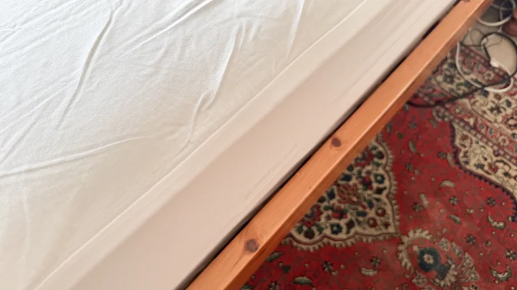 A closeup of the side edge of the Panda Bamboo mattress protector, on a mattress