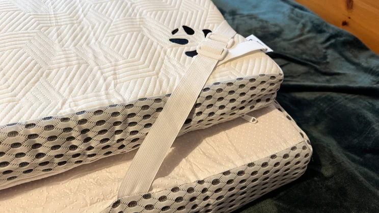 The Panda Hybrid Bamboo Mattress topper folded over on itself after unpacking. A corner strap is holding it together