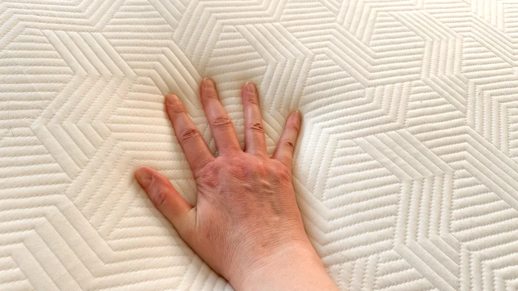 A closeup on the surface of the Panda Hybrid Bamboo Mattress topper, with a hand pressing down on it