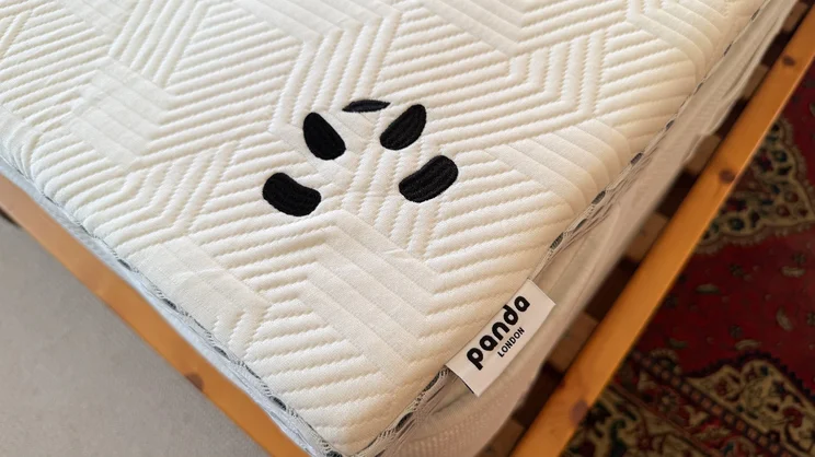 A bird's eye view of a corner of the Panda Hybrid Bamboo Mattress topper, showing the Panda logo and label