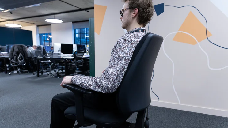 Viewed from the side, a person sits neutrally in the Posturite Homeworker Plus office chair