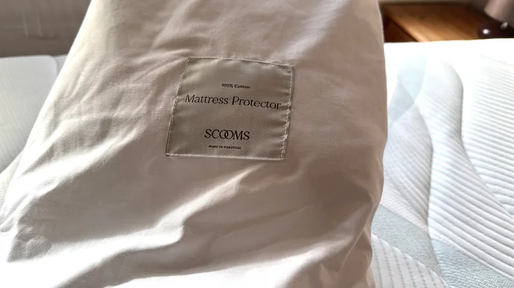 A closeup of the Scooms 100% Pure Cotton mattress protector's storage bag