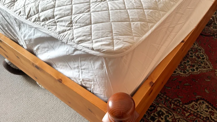 A closeup of the bottom corner of the Scooms 100% Pure Cotton mattress protector, on a mattress