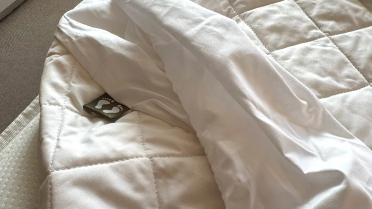 A closeup of the Scooms 100% Pure Cotton mattress protector, partially covering the surface of a mattress