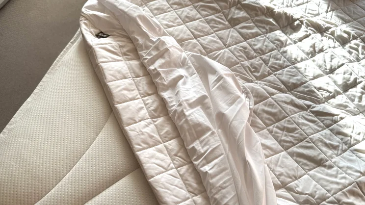 A closeup of the Scooms 100% Pure Cotton mattress protector, partially covering the surface of a mattress