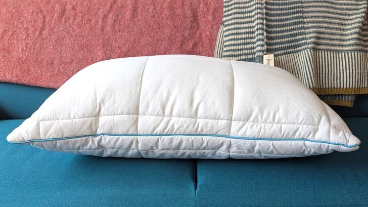 A side view of the Simba Aerodown pillow, on a blue sofa
