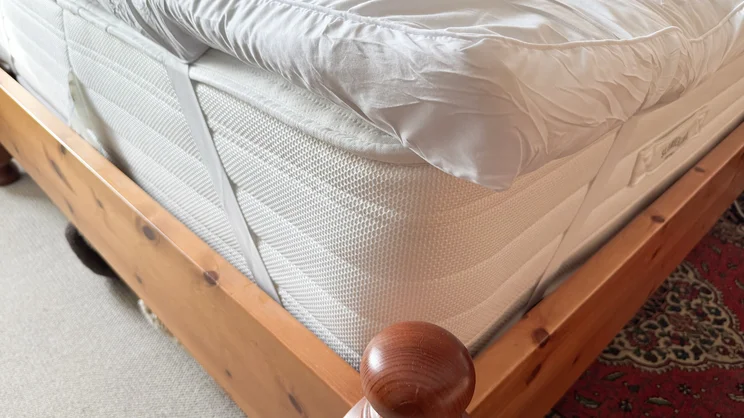 A closeup of the The Slumberdown Sleep Soundly Extra Deep Climate Control mattress topper's corner and elasticated strap holding it on the mattress