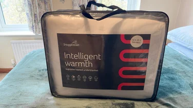 The Snuggledown Intelligent Warmth electric blanket in its bag, on a mattress