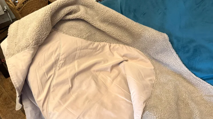 The Stoov Huge Hug 3 electric blanket draped over a blue sofa