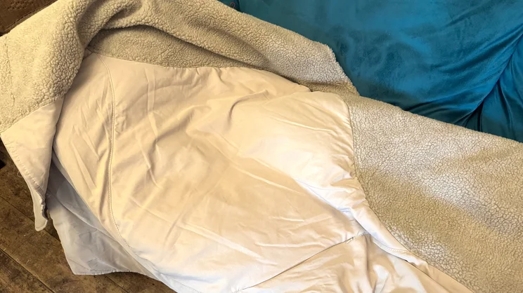 The Stoov Huge Hug 3 electric blanket draped over a blue sofa