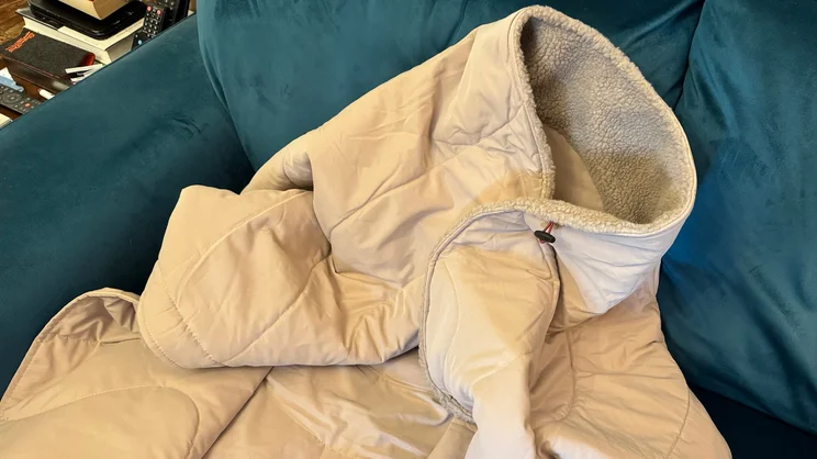 The Stoov Huge Hug 3 electric blanket, with toggles fastened, draped over a blue sofa