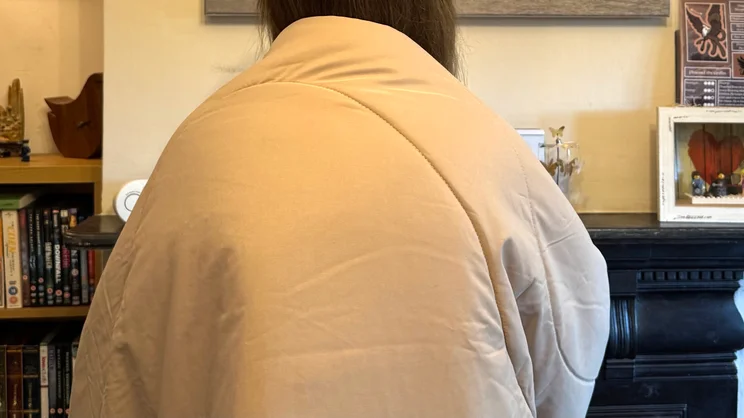 The Stoov Huge Hug 3 electric blanket draped over the writer's shoulders, viewed from the back